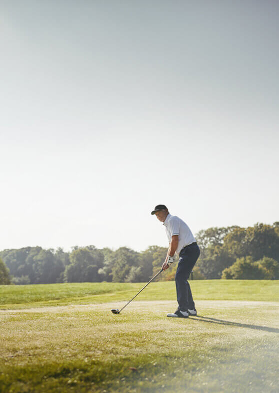 Golfer im Ansprechhaltung auf grünem Platz.