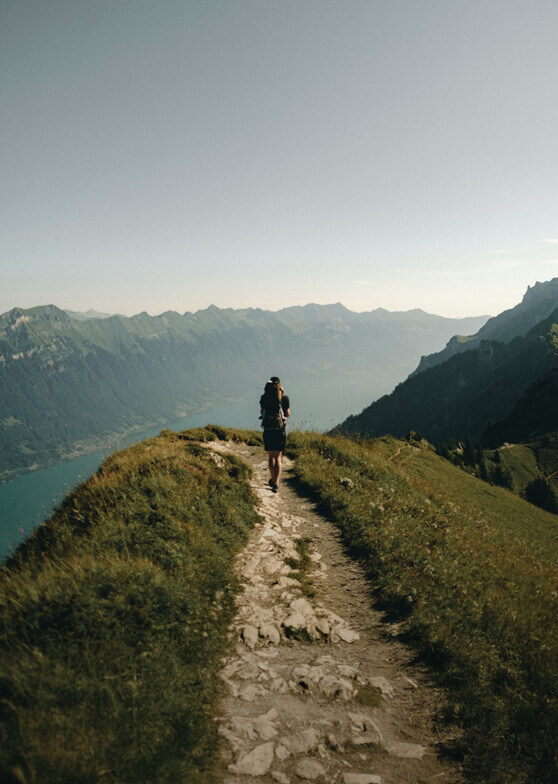 Wanderer mit Rucksack auf Bergpfad mit Seeblick.