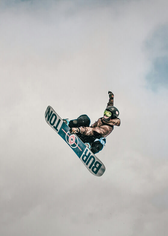 Snowboarder springt vor bewölktem Himmel.