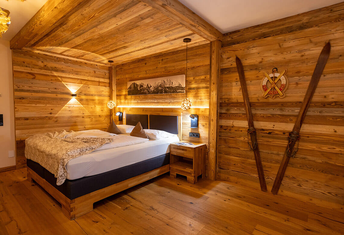 Alpines Schlafzimmer aus Holz mit Bett und Skiern.