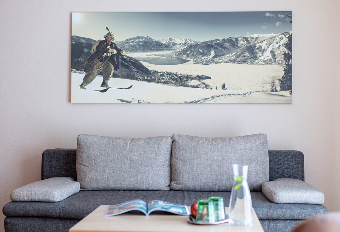 Skifahrer in Tracht vor winterlicher Berglandschaft mit See.