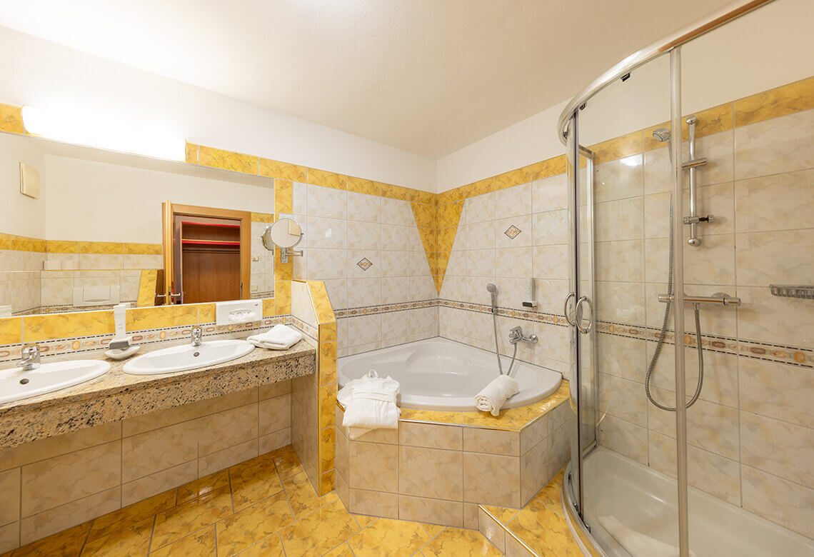 Gelb gefliestes Bad mit Doppelwaschbecken, Wanne, Dusche.