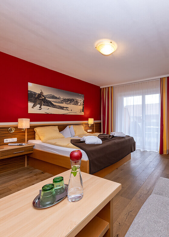 Hotelzimmer mit Bett, roter Wand und Fenster.