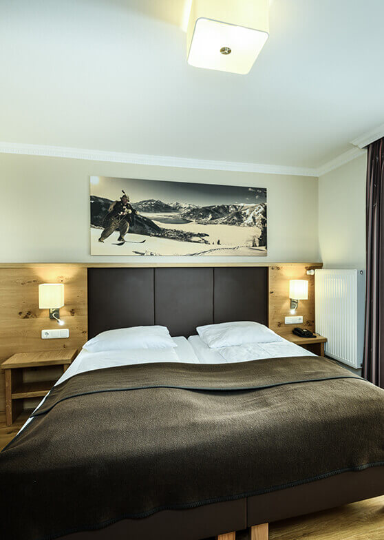 Schlafzimmer mit Doppelbett und Skifahrer-Wandbild.