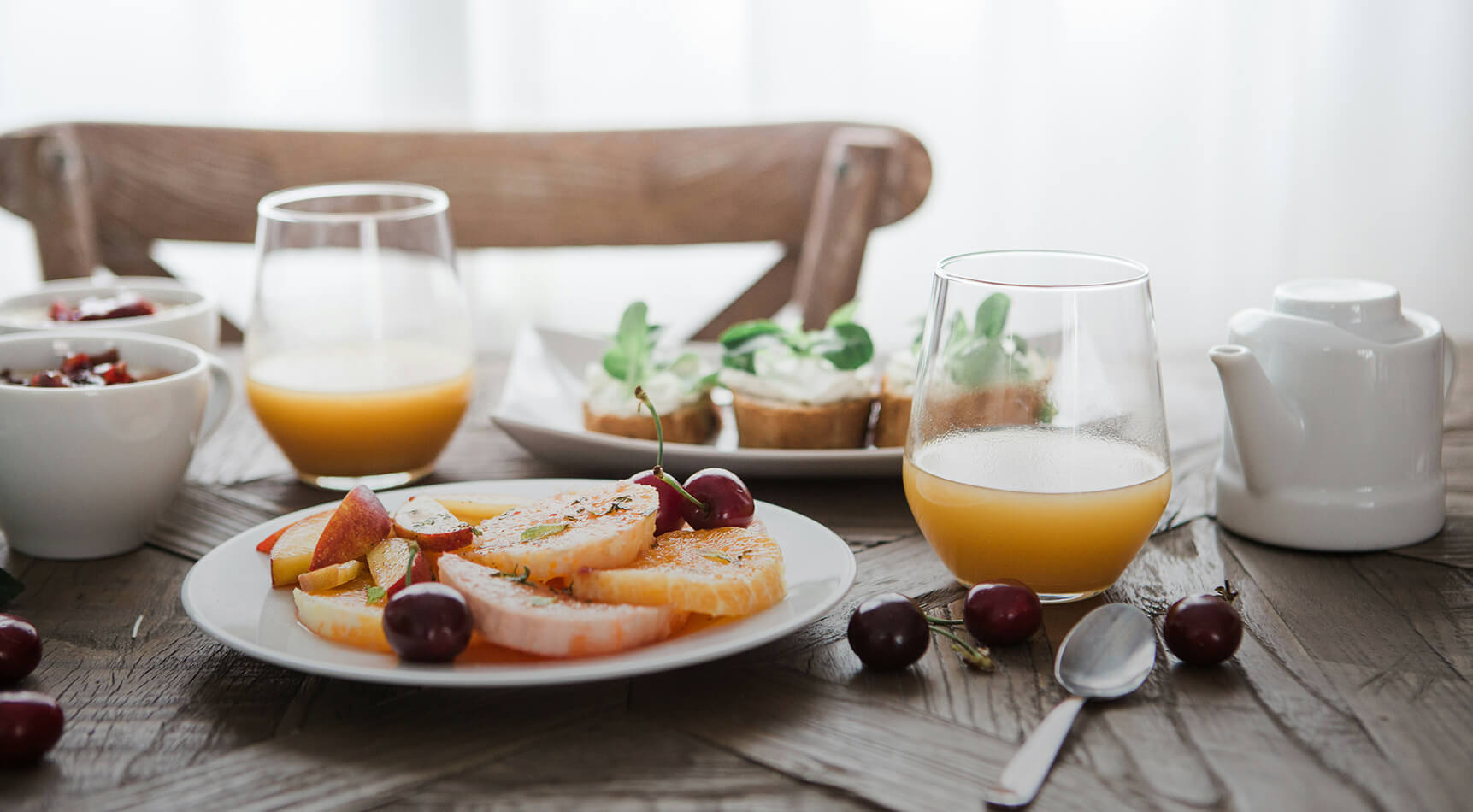 Frühstück mit Früchten, Saft, Toast und Teekanne.