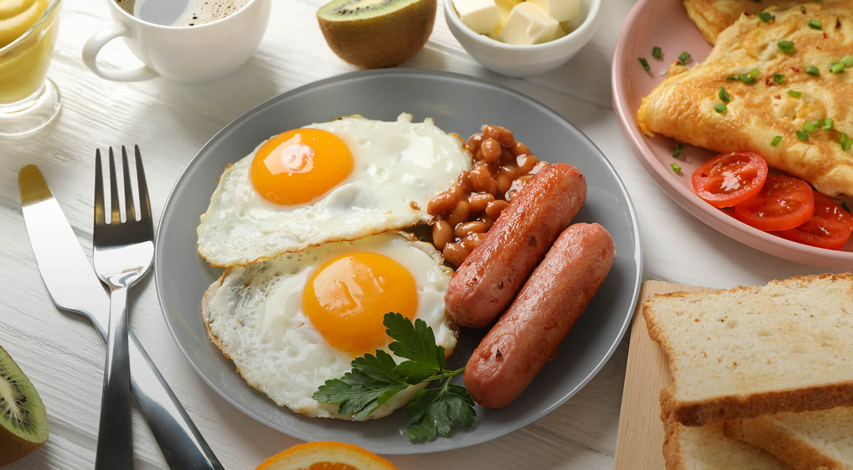 Frühstück mit Spiegeleiern, Würstchen und Bohnen auf Teller.