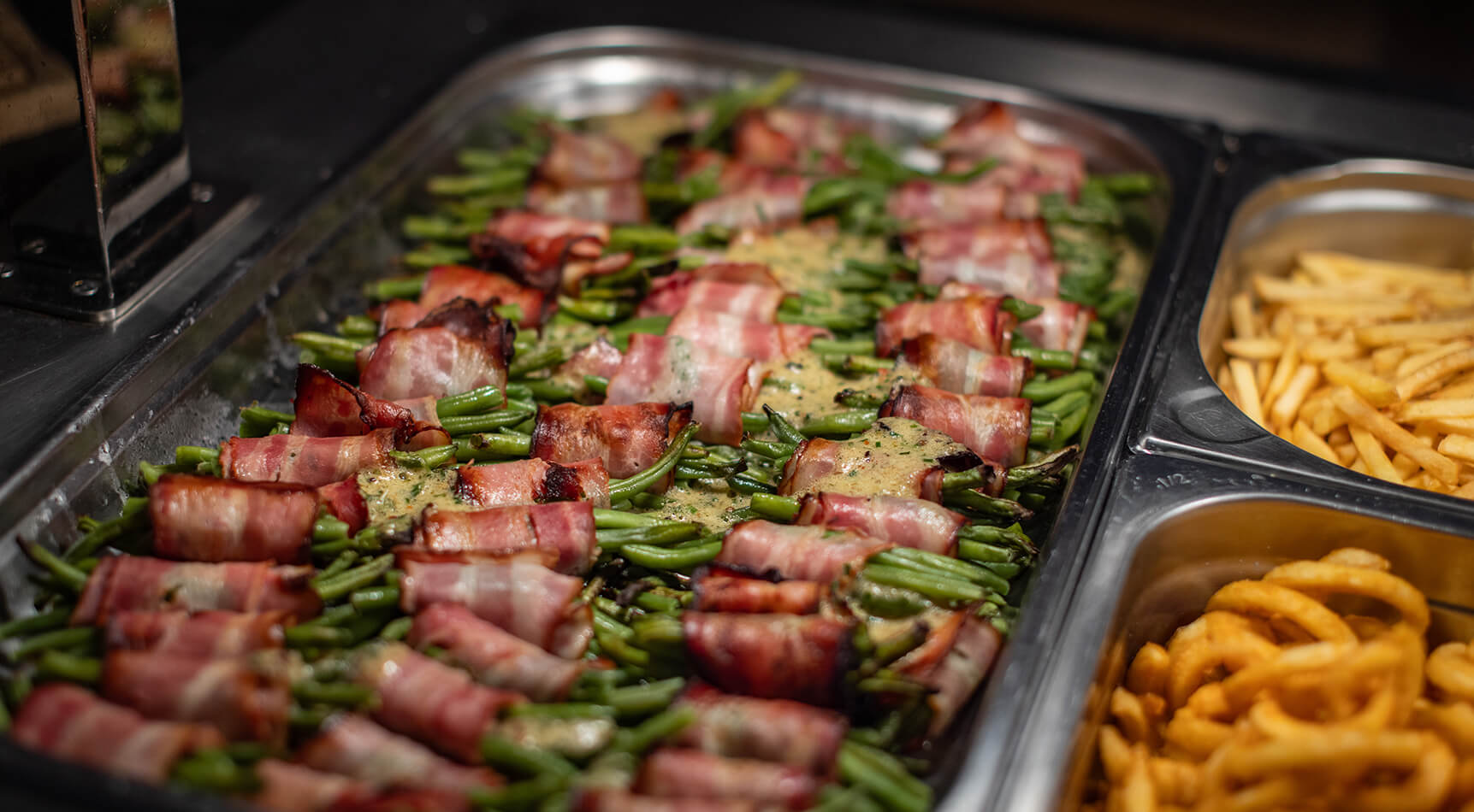 Grüne Bohnen im Speckmantel mit Sauce und Pommes.