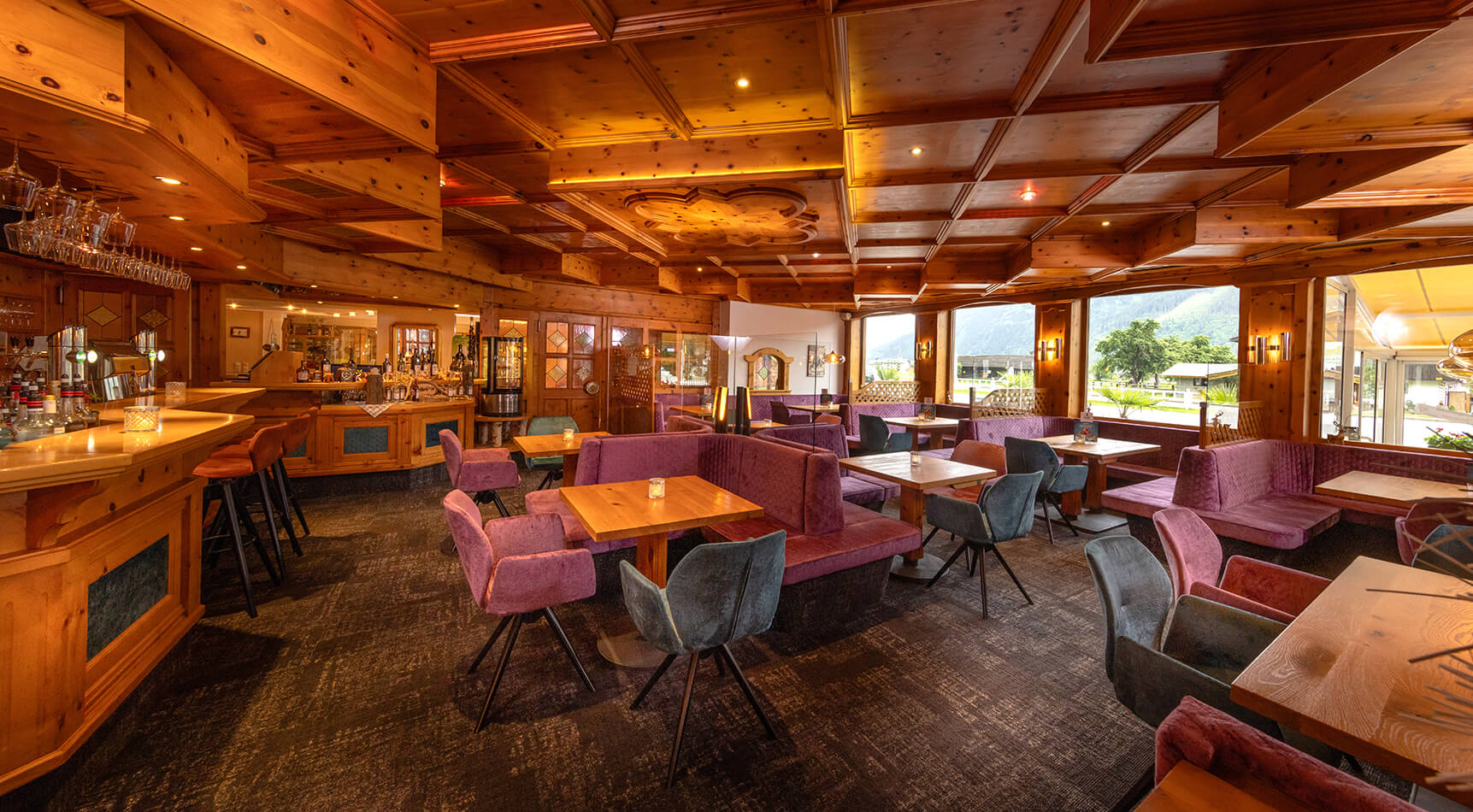 Rustikales Restaurant mit Holzvertäfelung und lila Sitzgruppen.