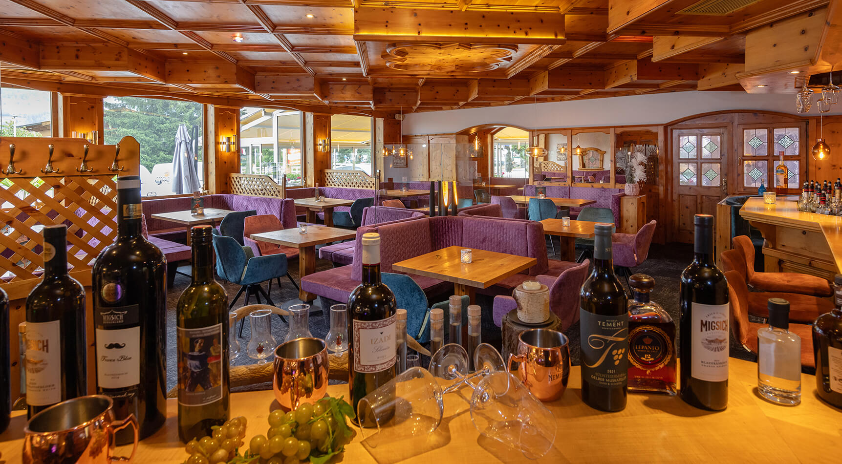 Rustikales Restaurant mit Tischen, Bar und Weinflaschen.