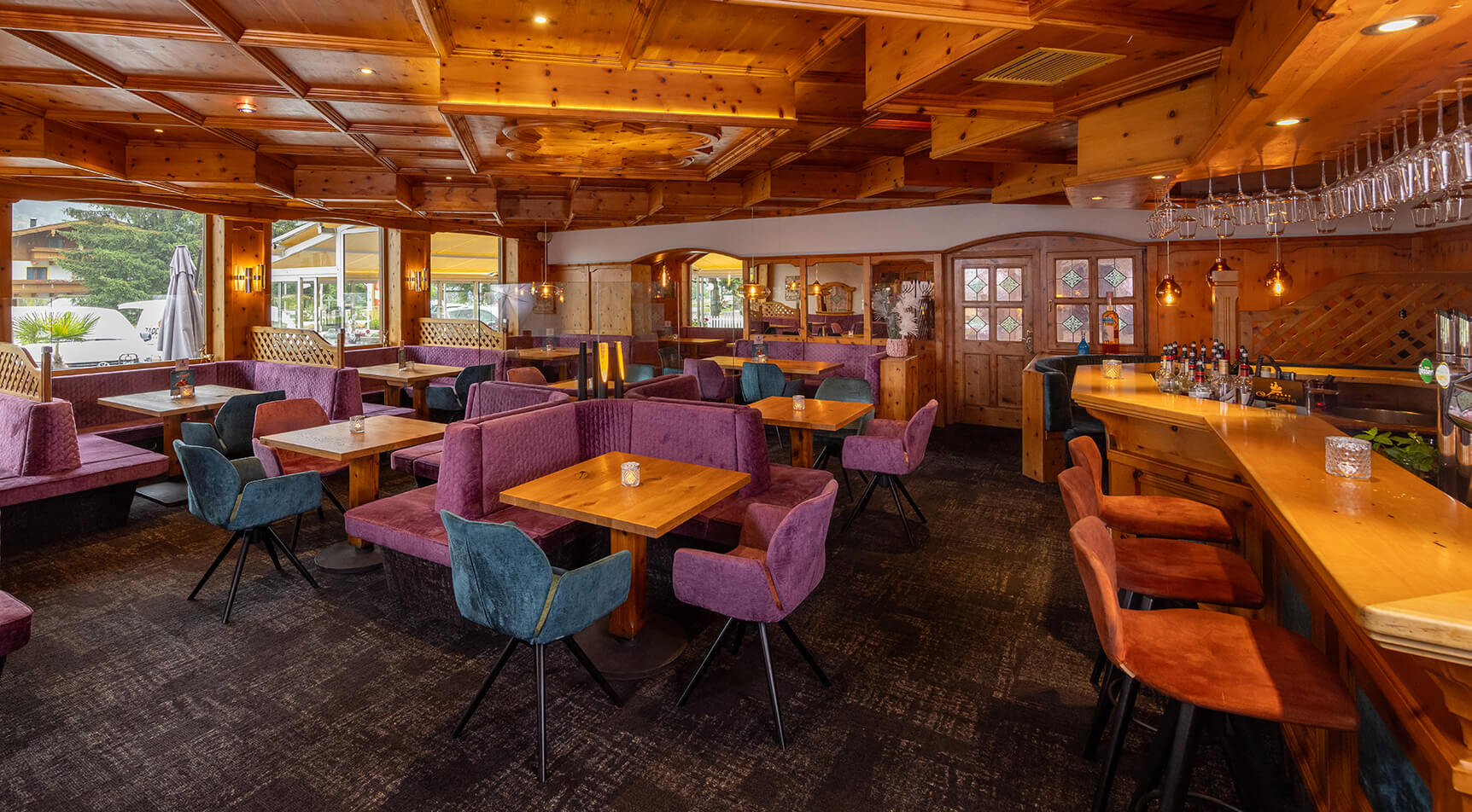 Holzgetäfeltes Restaurant mit violetten Sitzbänken und Bar.