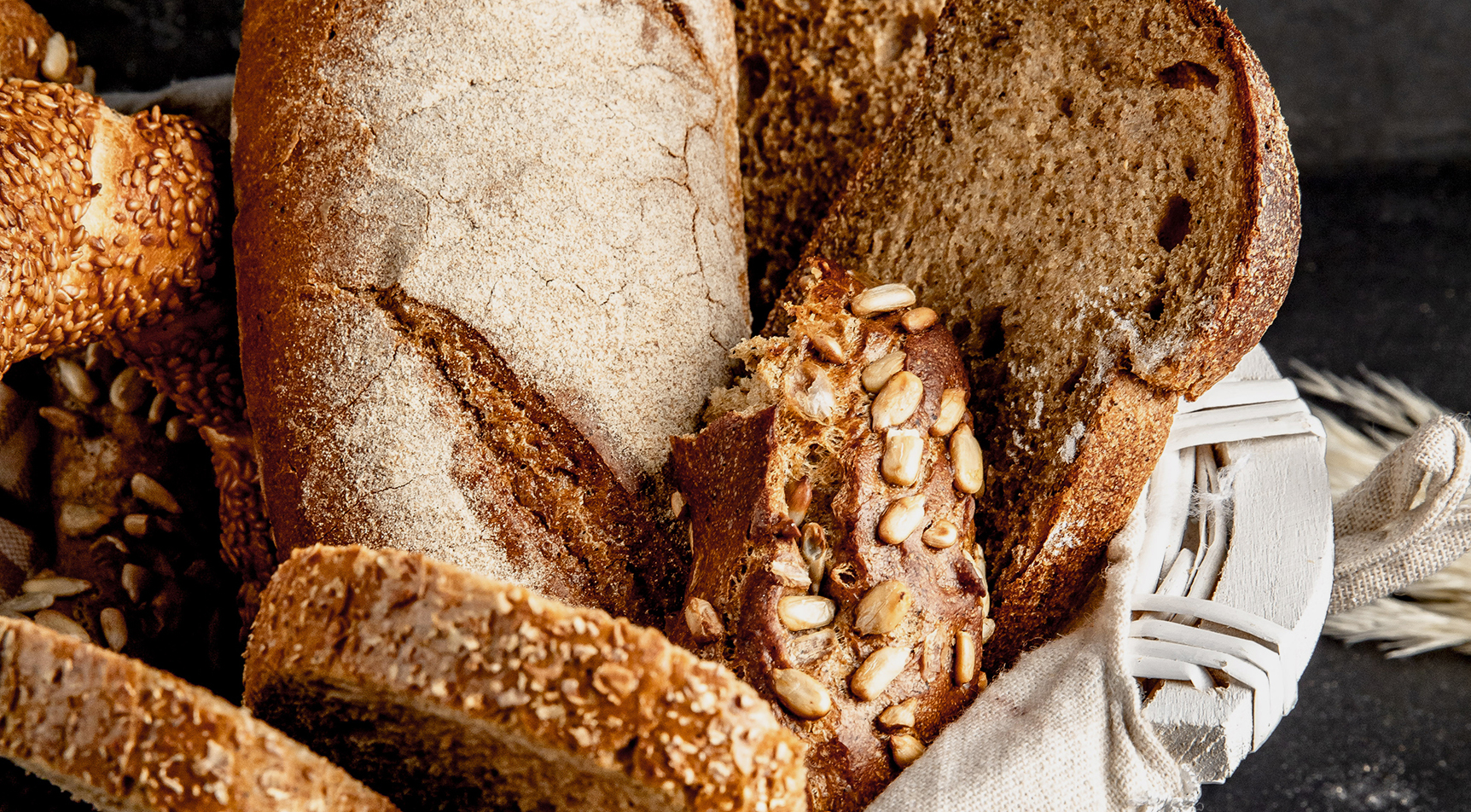 Brotlaibe und Brötchen mit Saaten in einem Korb.