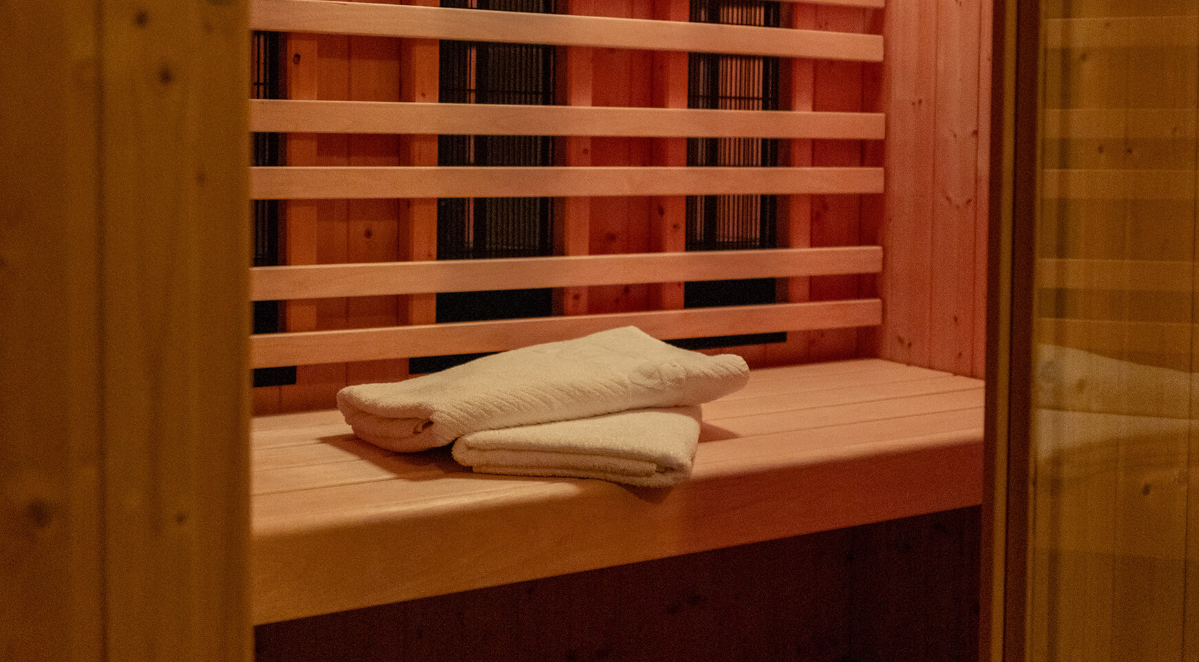 Zwei gefaltete Handtücher auf Holzbank in Infrarotkabine.