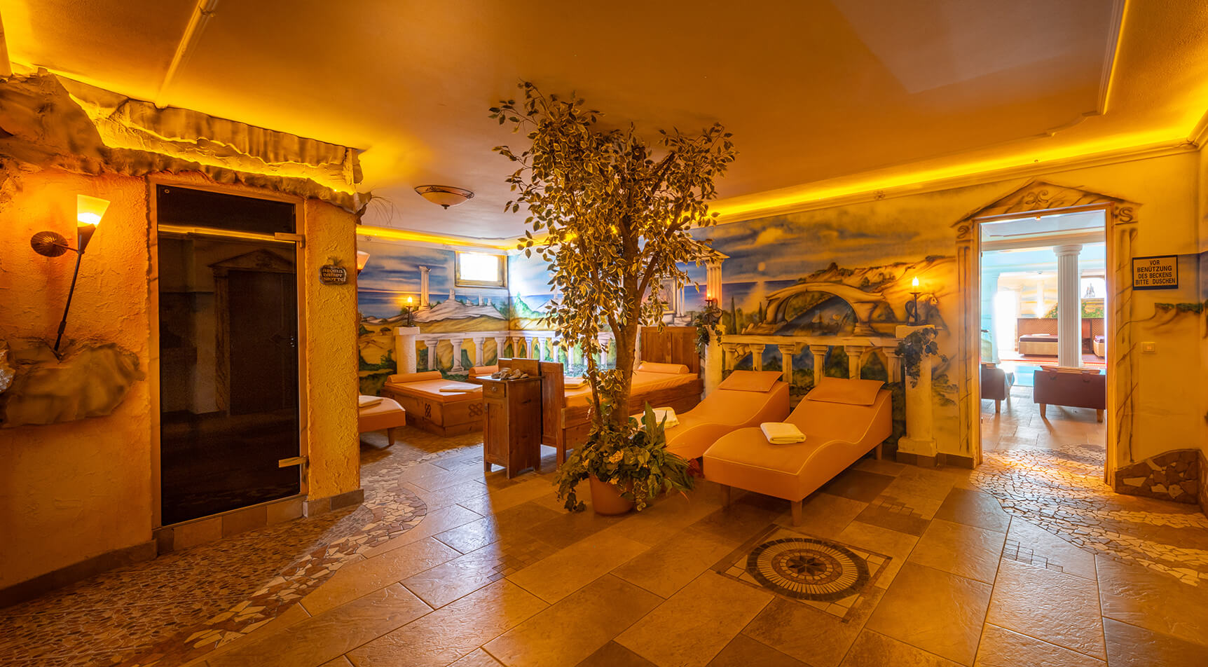 Spa-Raum mit Baum, Liegen und Wandmalereien.