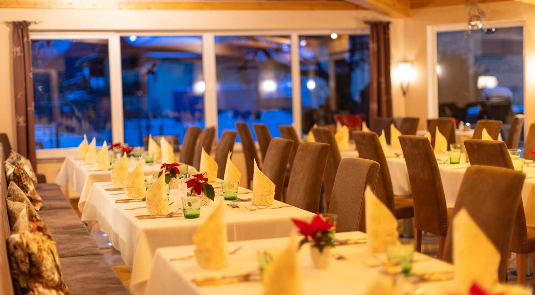 Gedeckter Speisesaal mit Tischen, Stühlen, Servietten, Blumen.